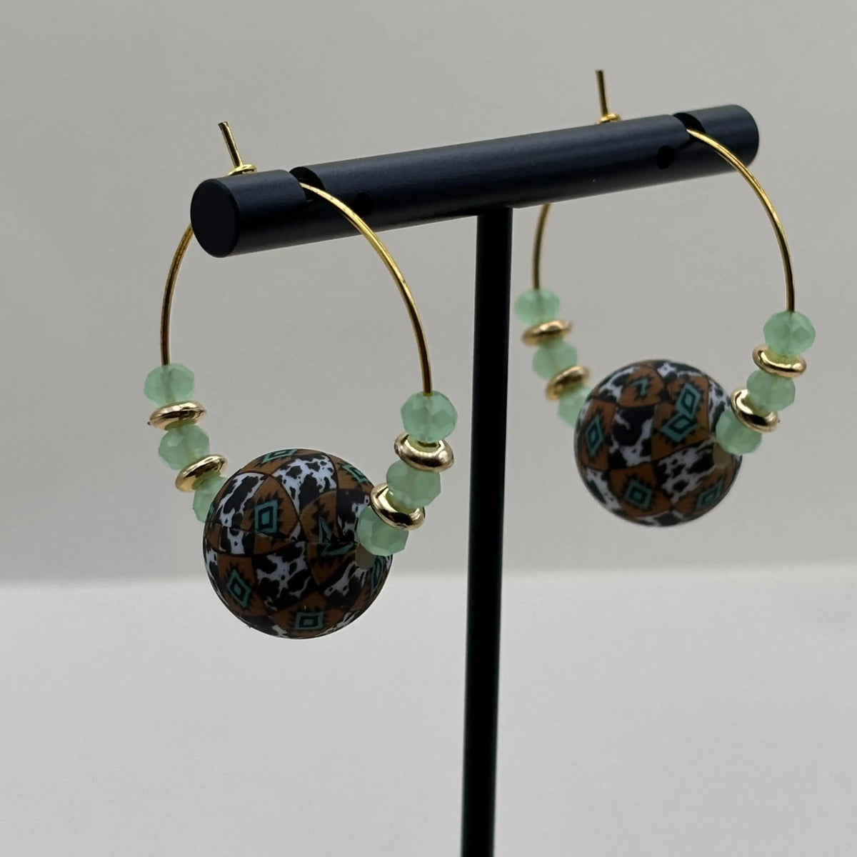 Des boucles d'oreilles créole artisanales dorées avec breloque centrale colorée et perles vert d'eau
