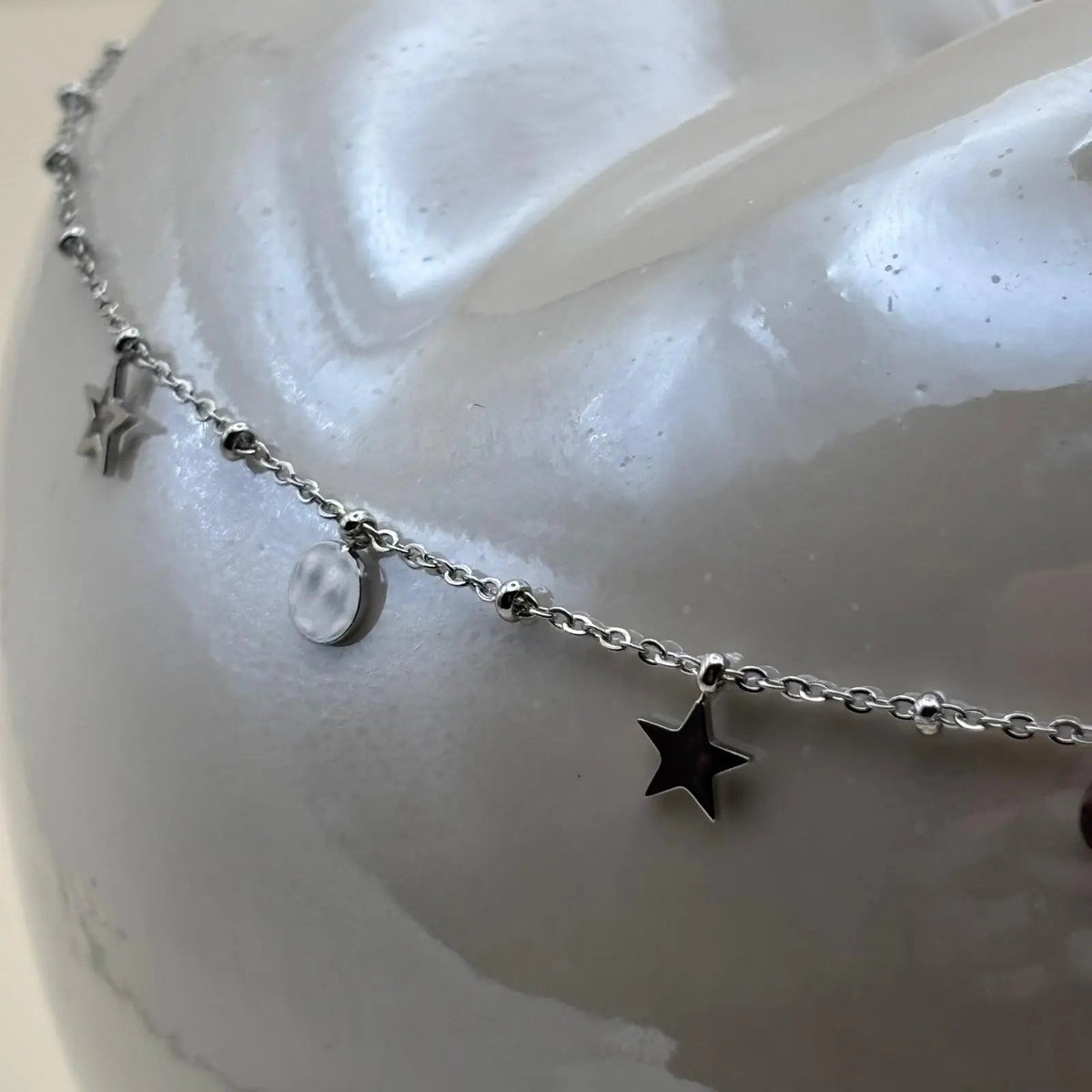 Un collier argenté avec breloques fleurs lune étoile et soleil en acier inoxydable 