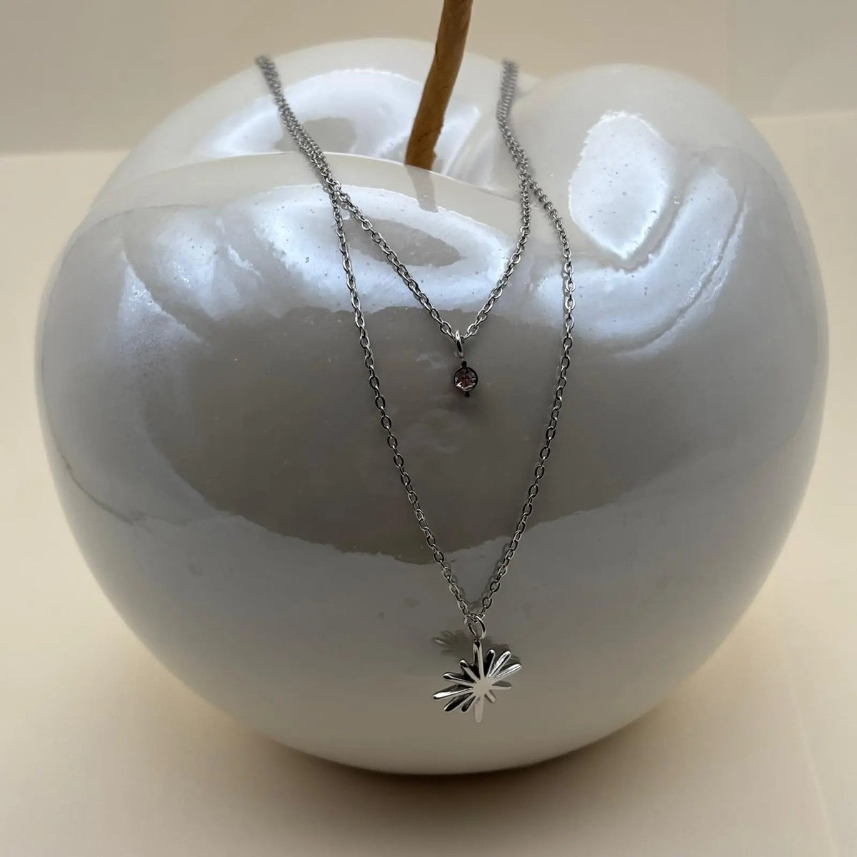 Un collier multirangs argenté avec double chainette un pendentif brillant et un pendentif soleil en acier inoxydable