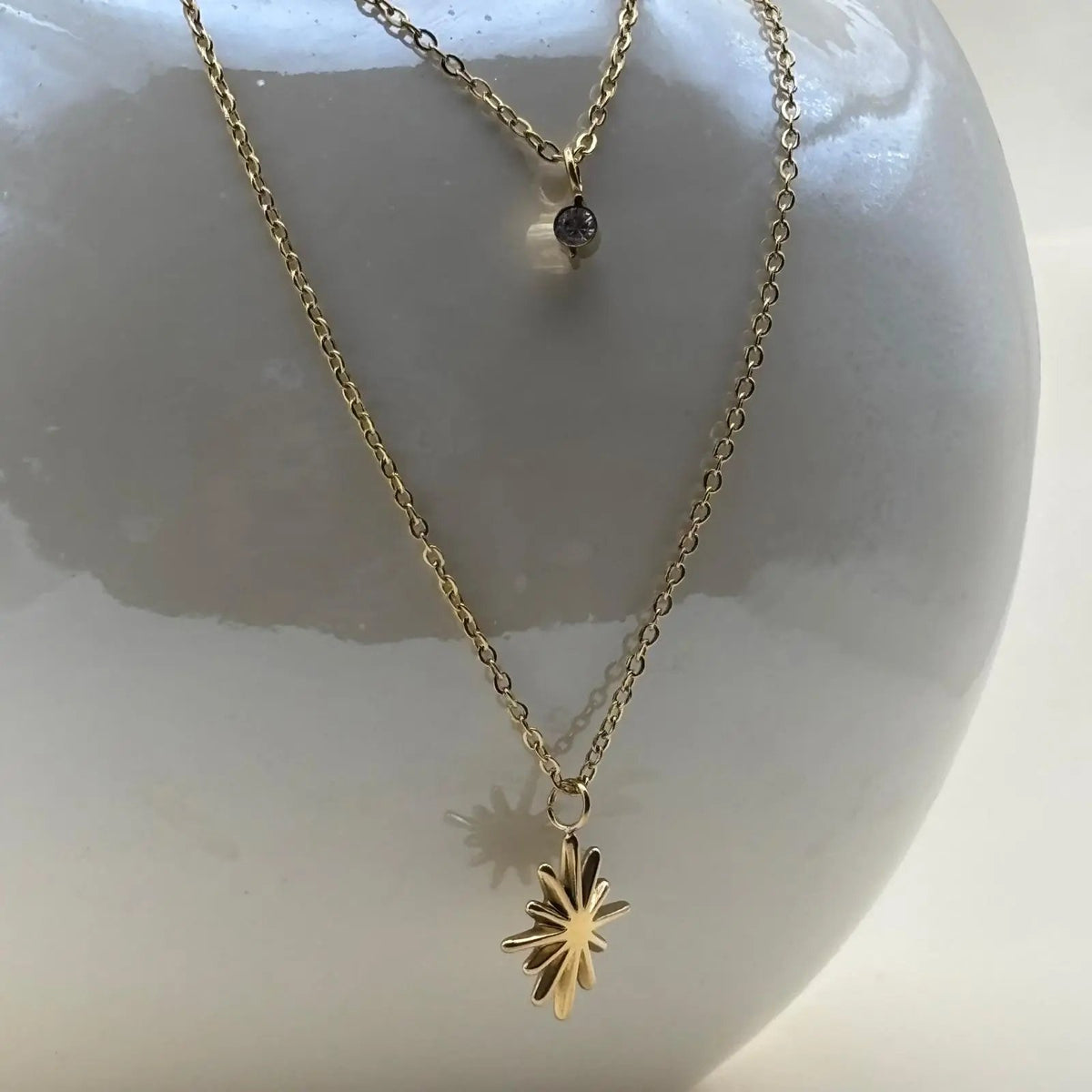 Un collier multirangs doré avec double chainette un pendentif brillant et un pendentif soleil en acier inoxydable 