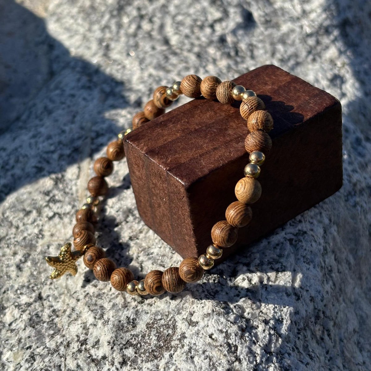 Bracelet en perles artisanal avec une breloque étoile de mer dorée  et des perles en bois sur élastique
