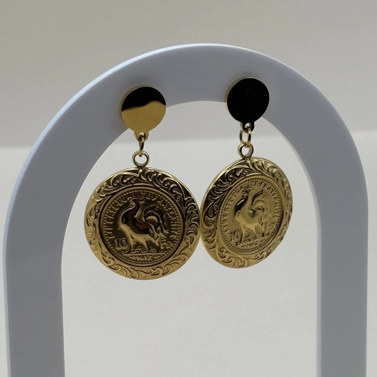 Bague dorée avec le symbole du coq français dans une forme ronde et un pourtour géométrique