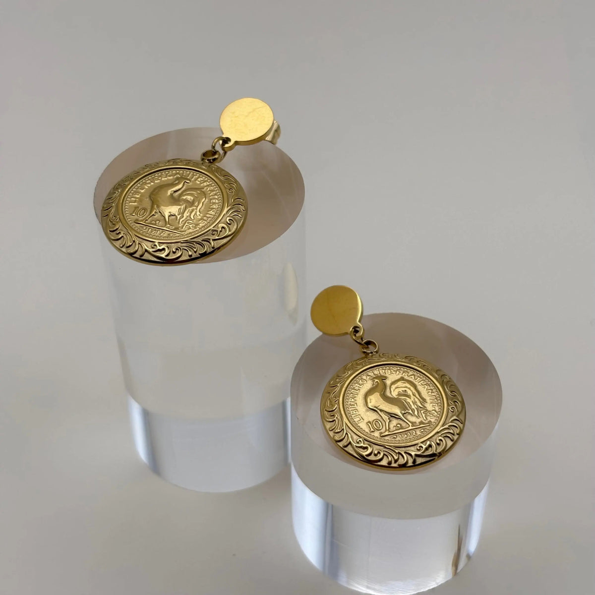 Une bague dorée avec le symbole du coq français dans une forme ronde et un pourtour géométrique