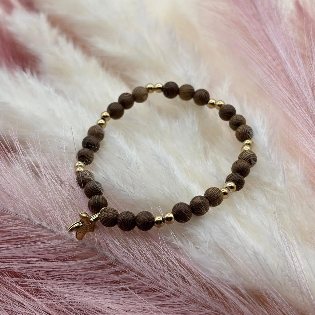 Bracelet en perles artisanal avec une breloque étoile de mer dorée  et des perles en bois sur élastique
