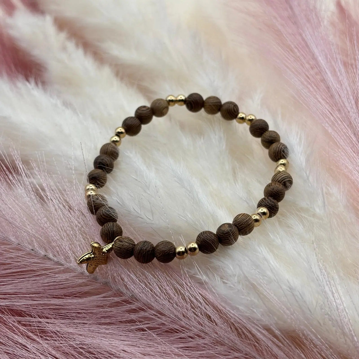 Bracelet en perles artisanal avec une breloque étoile de mer dorée  et des perles en bois sur élastique