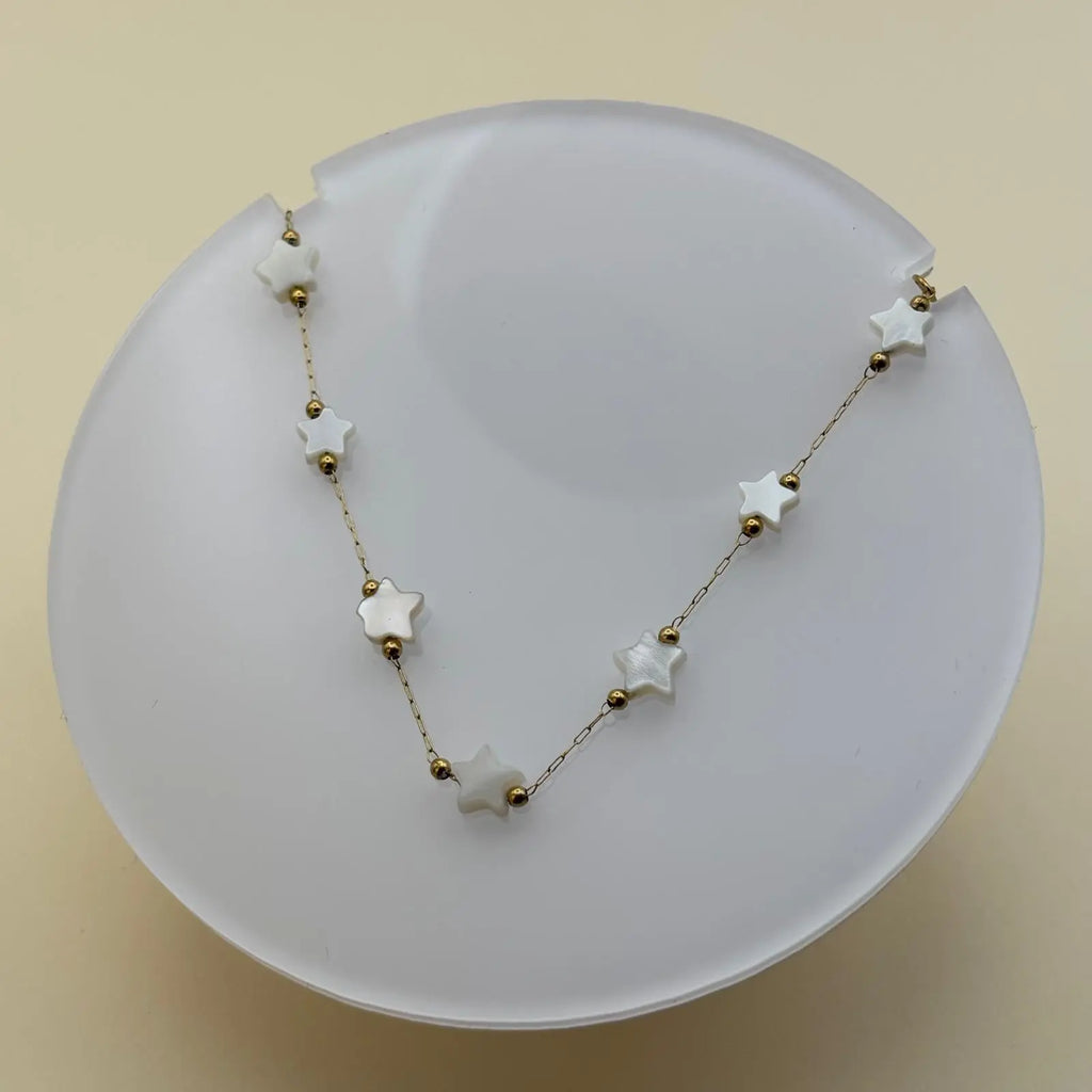 Bracelet doré à petits maillons avec breloques en forme d'étoiles blanches 