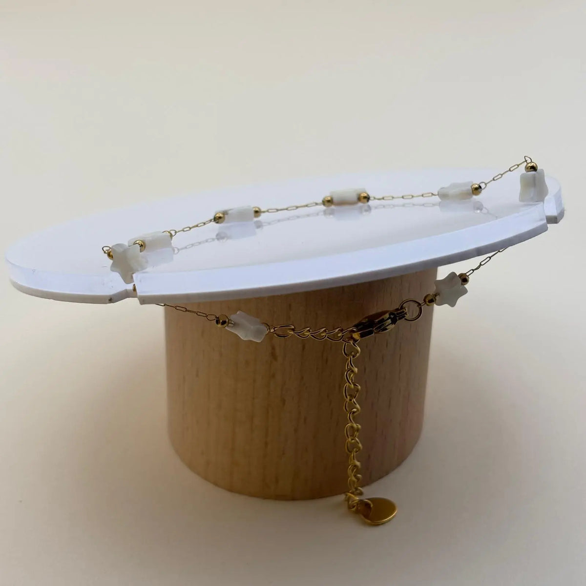 Bracelet doré à petits maillons avec des breloques en forme d'étoiles blanches  et de petites perles dorées