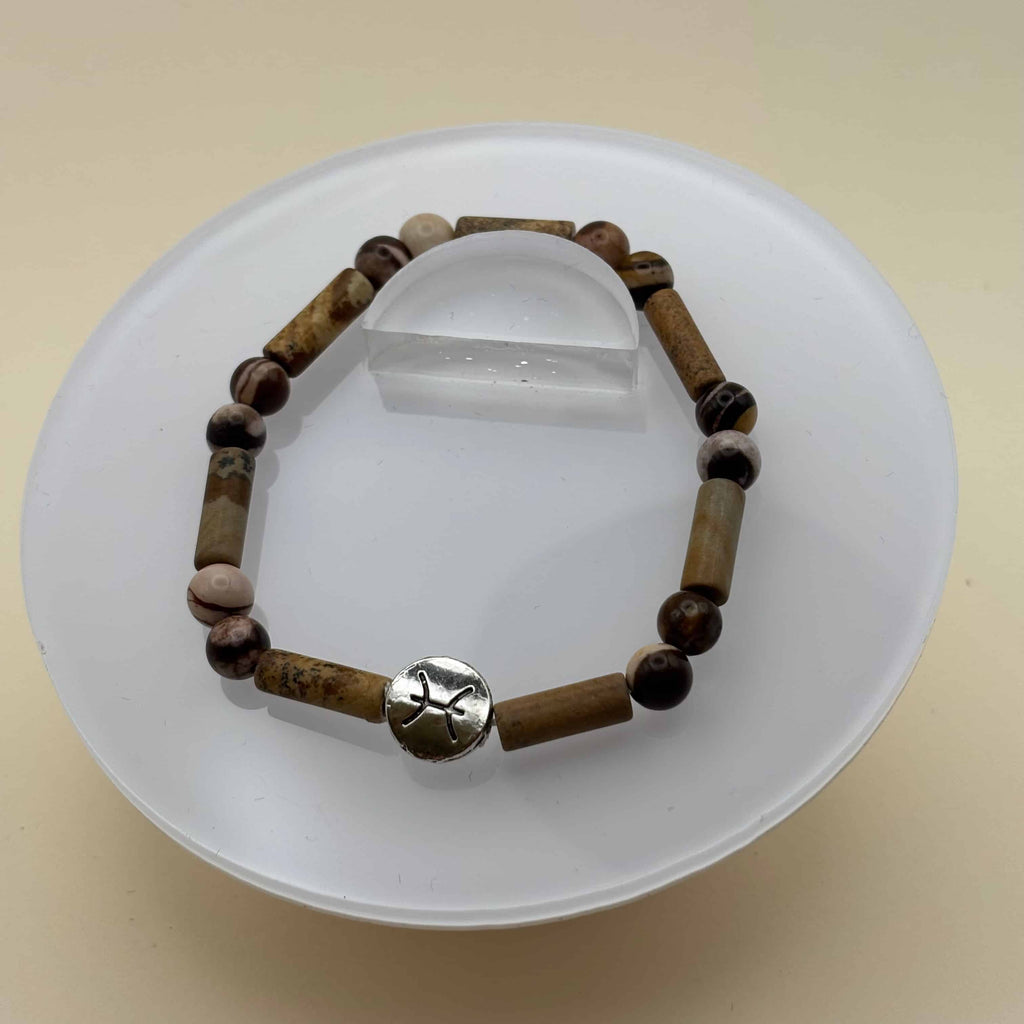 Un bracelet en perles sur élastique avec perles en porcelaine et en verre et médaillon avec le signe du poisson