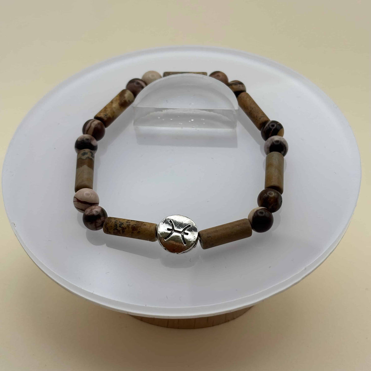 Un beau bracelet en perles sur élastique avec perles en porcelaine et en verre et médaillon avec le signe du poisson