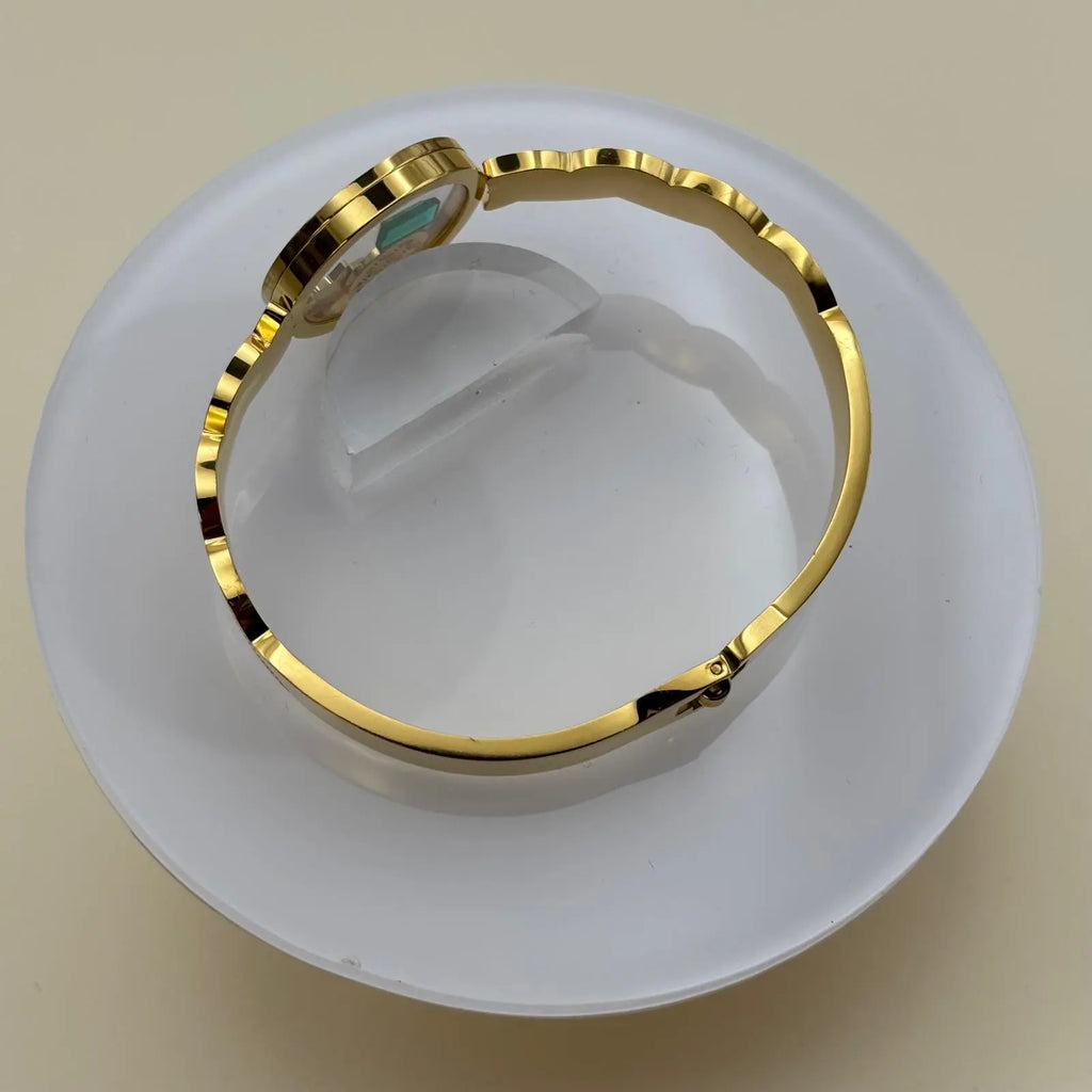 Bracelet couleur doré à jonc ouvert avec cercle central transparent rempli d'éléments décoratifs et ouverture par le dessous en acier inoxydable