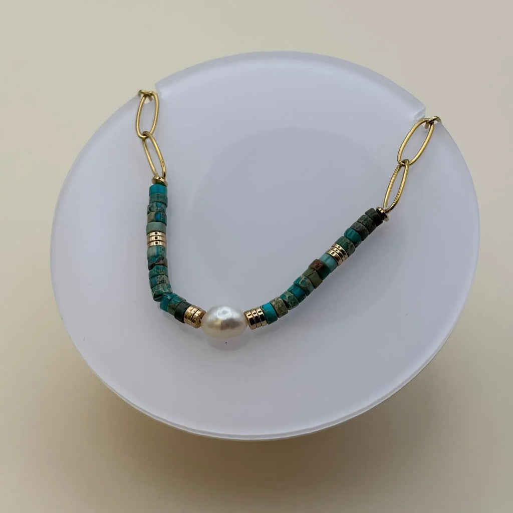 Bracelet doré avec des perles acryliques bleues et une perle nacrée au centre 