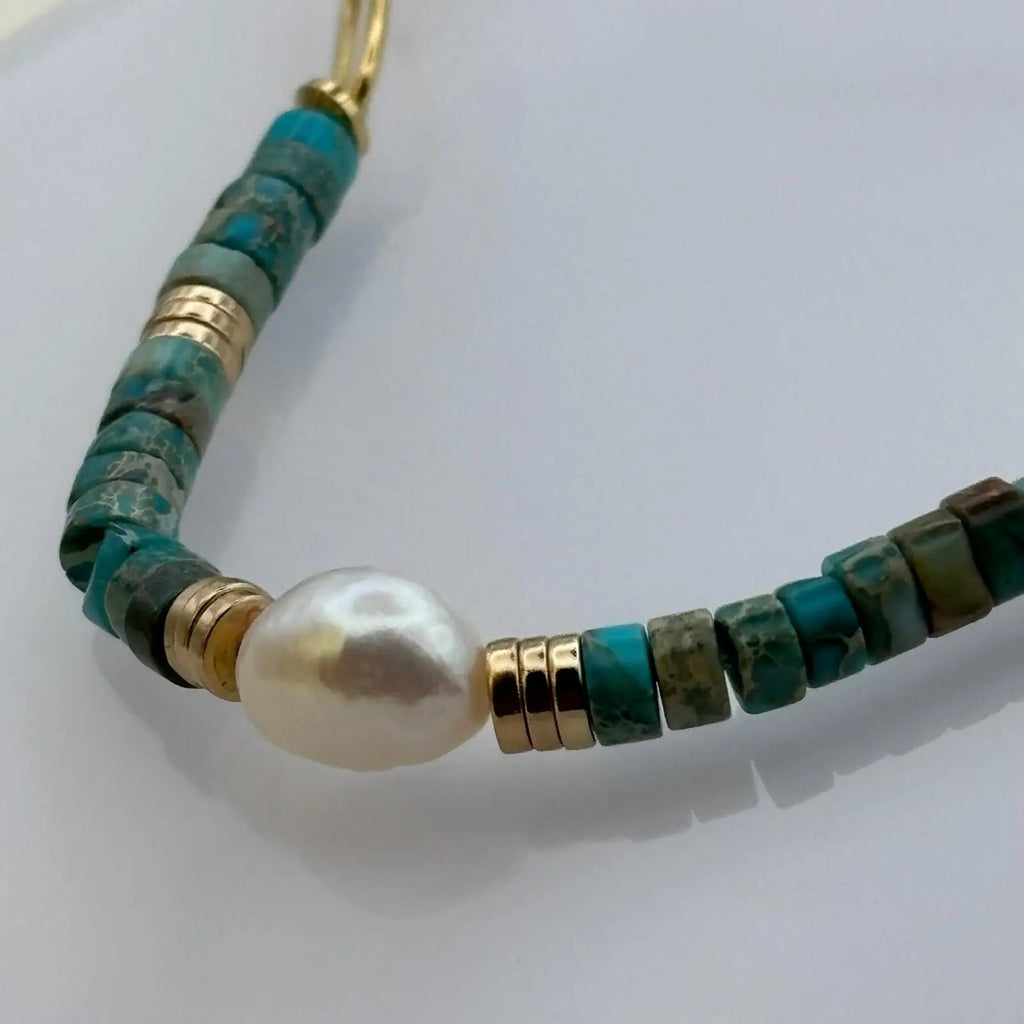 Bracelet doré avec perles acryliques bleues et une perle nacrée au centre 