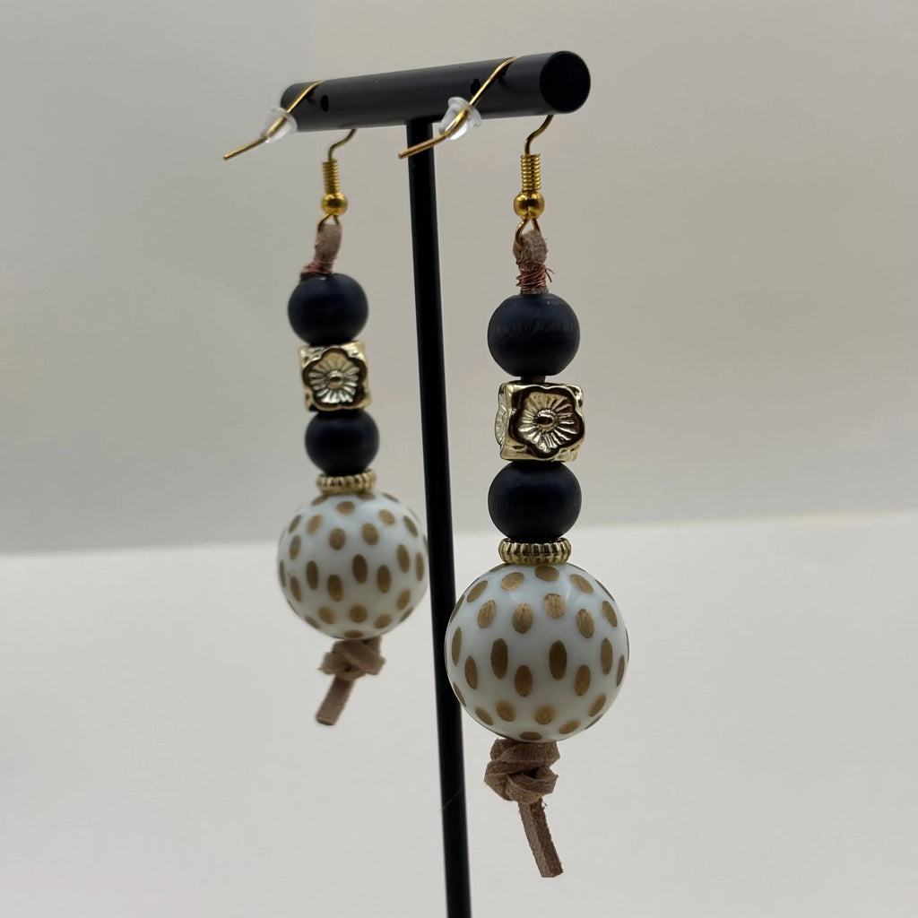 Des boucles d'oreilles pendentif avec perle marbrée blanche et or et perles  noires 