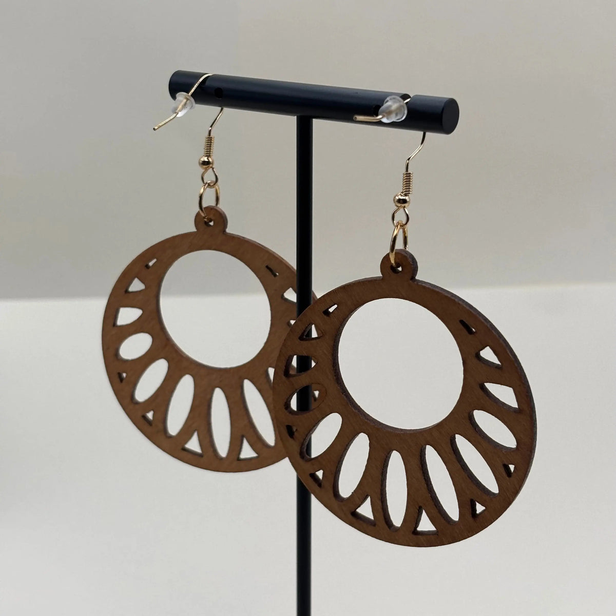 Des boucles d'oreilles attache dorée avec boucle en bois léger motif ajourée en forme de cercle