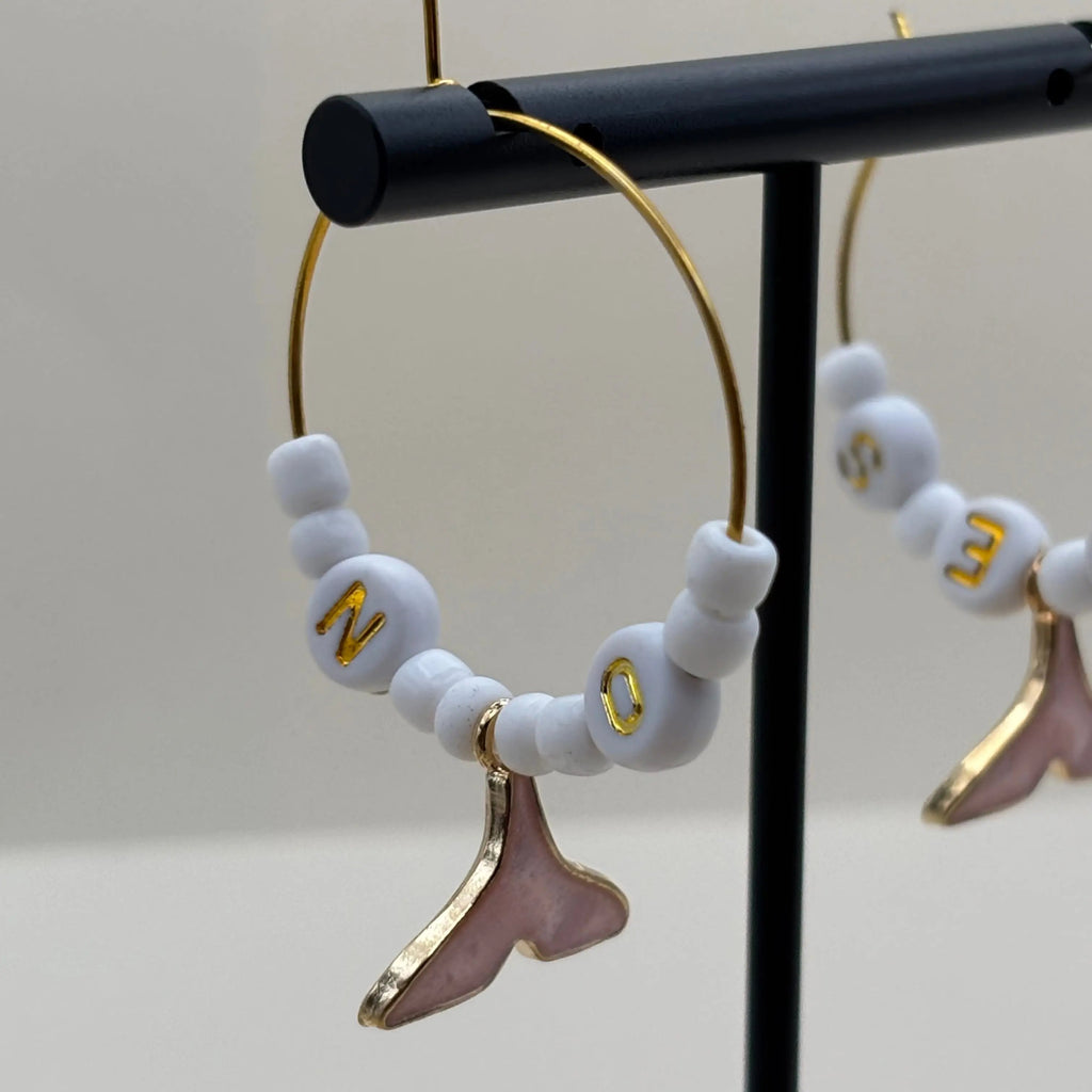 Boucles dorées à perles blanches et queux de baleine roses suspendues et les mots oui et non inscrit sur des perles 