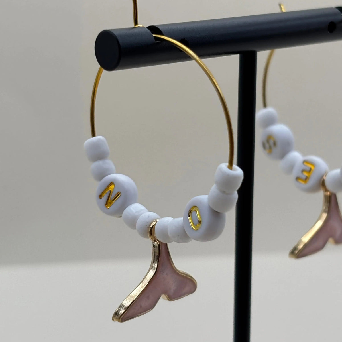 Boucles dorées à perles blanches et queux de baleine roses suspendues et les mots oui et non inscrit sur des perles 