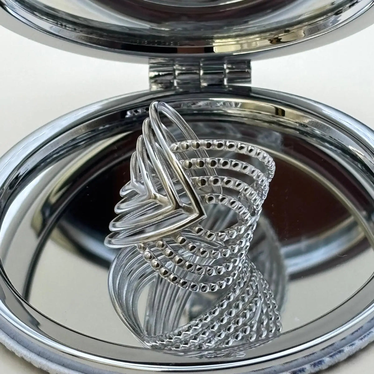 Bague argentée ajustable avec motifs géométriques en forme de volutes 