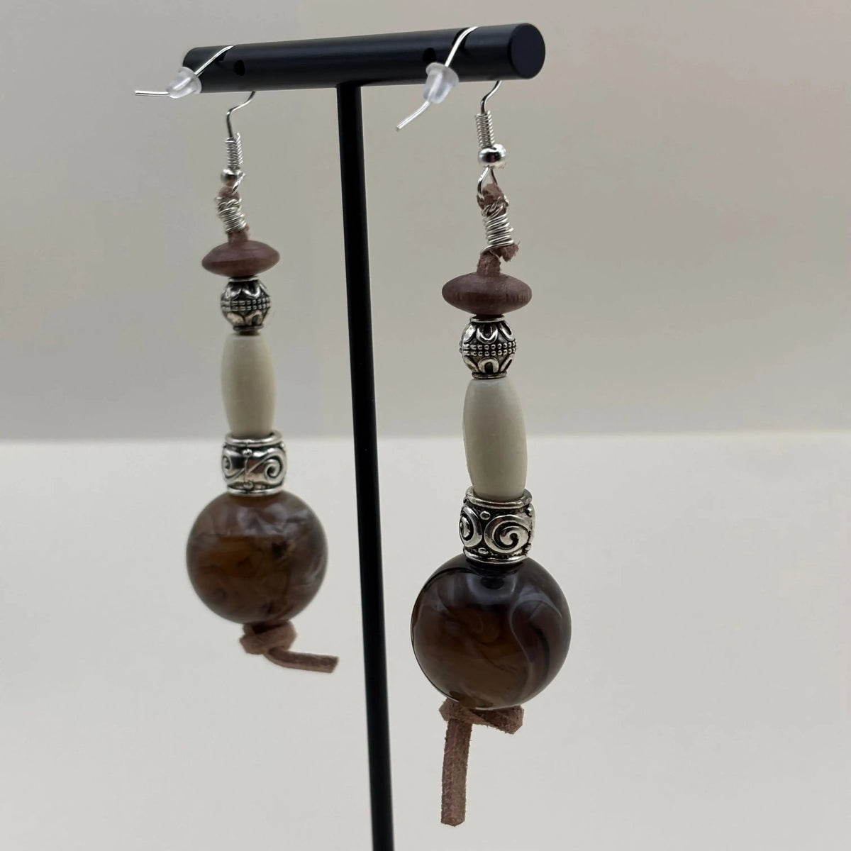 Des boucles d'oreilles artisanales argentée avec grosse perle marron et allongée blanche