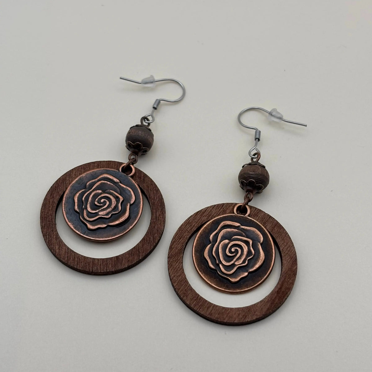 Une paire de boucles d'oreille en métal marron avec cercle et motif d'une fleur de rose