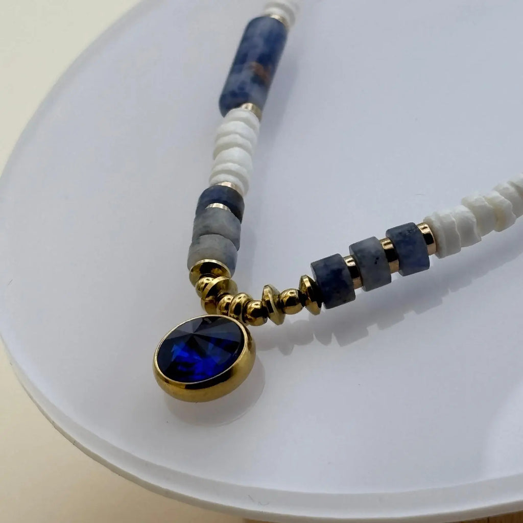 Bracelet doré avec perles acryliques blanches et bleues et un médaillon de couleur bleu profond