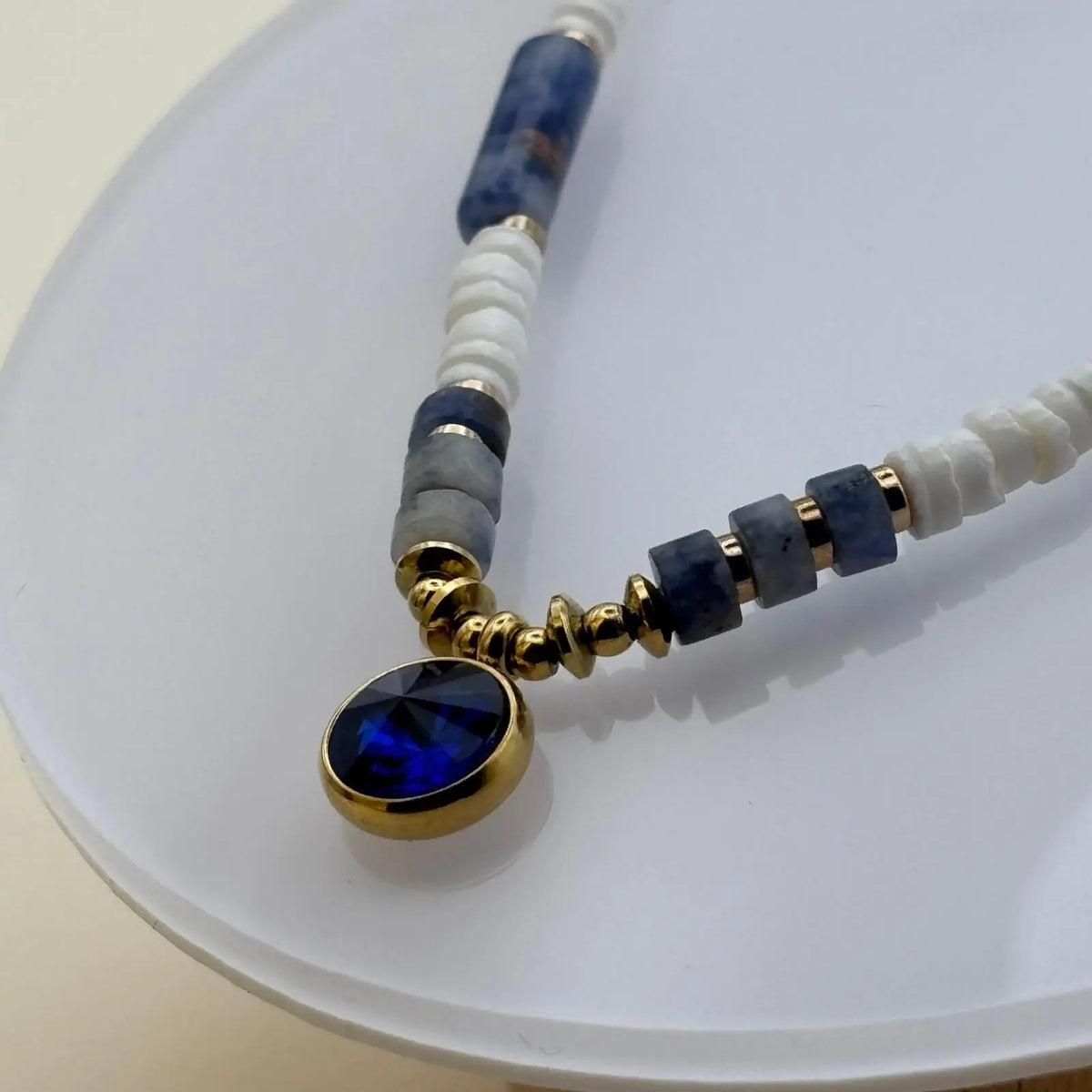 Bracelet doré avec perles acryliques blanches et bleues et un médaillon de couleur bleu profond