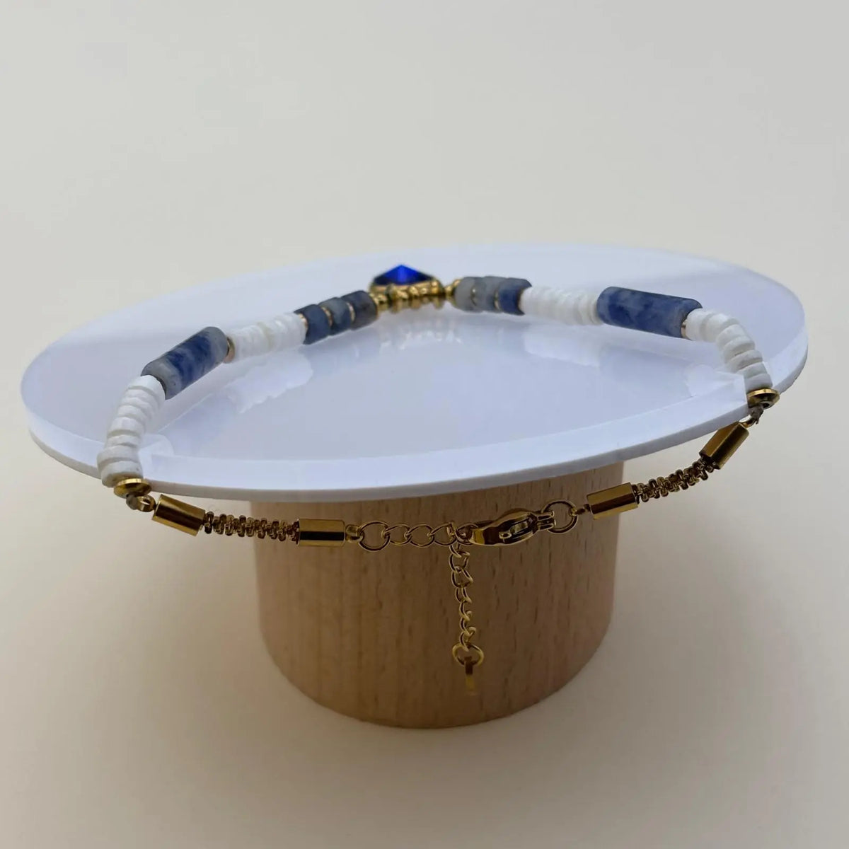 Bracelet doré avec des perles acryliques blanches et bleues et médaillon de couleur bleu profond