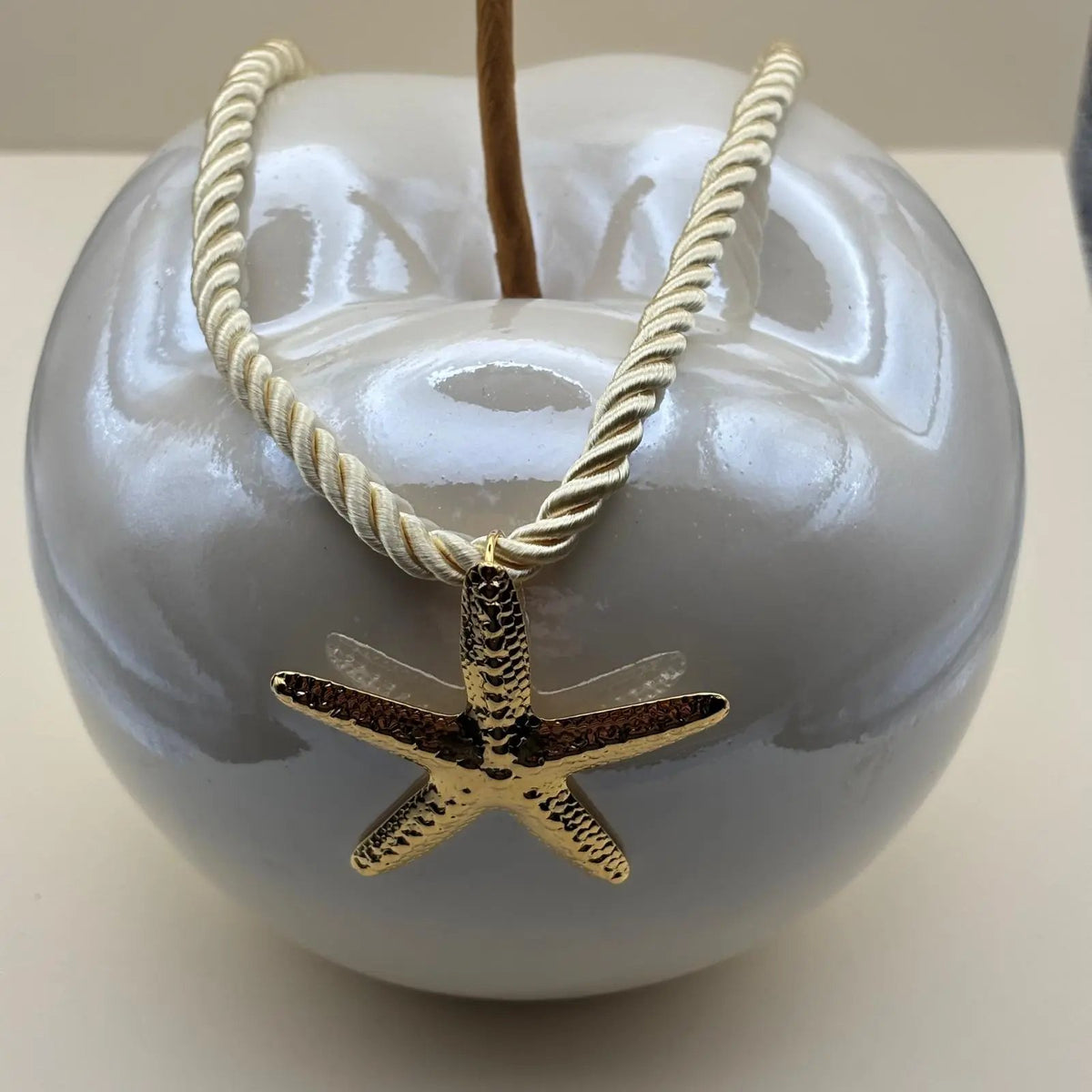 Un collier fantaisie avec corde nylon écrue et pendentif doré motif étoile de mer