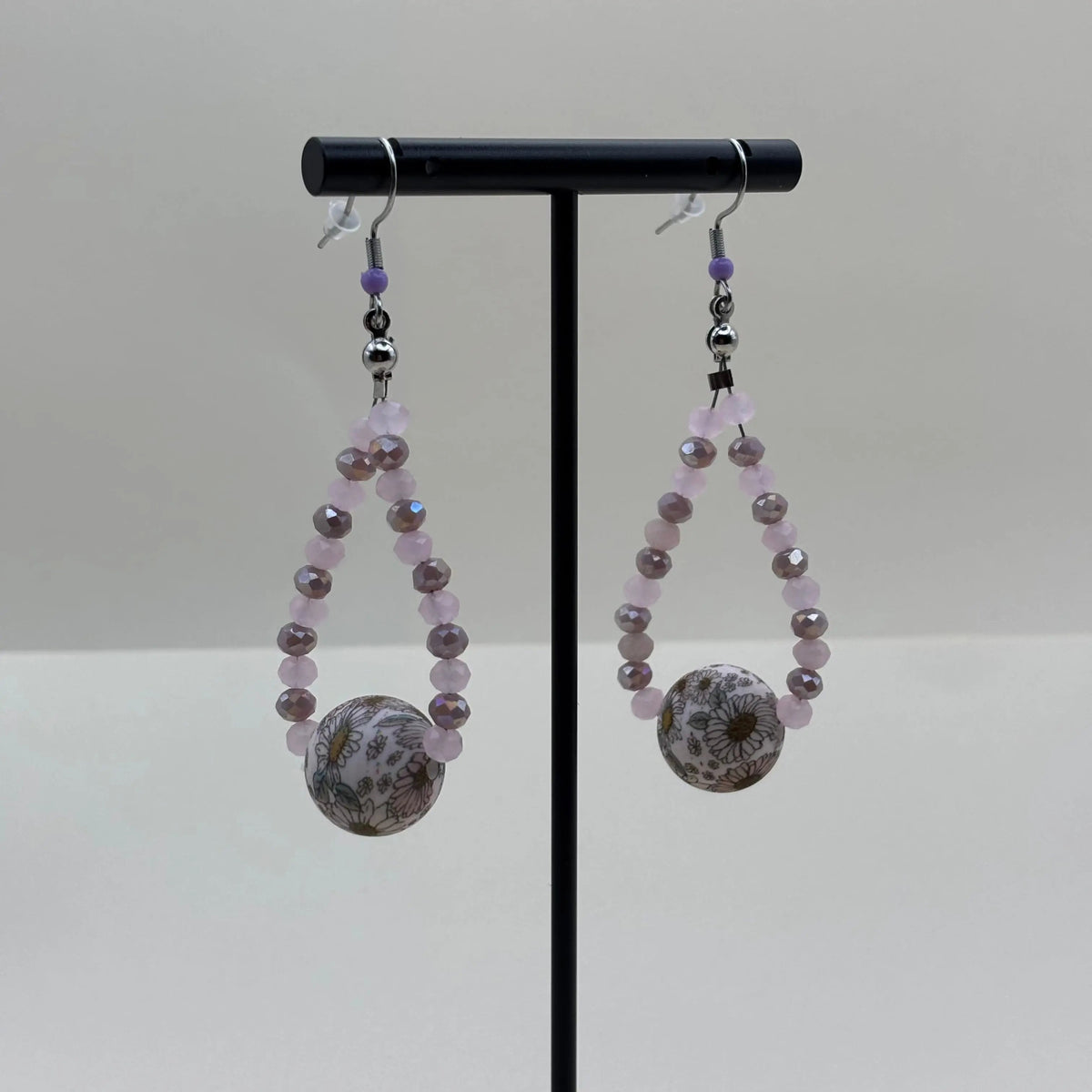 Boucles d'oreilles pendentif avec des petites perles mauves et une grosse perle fleurie 