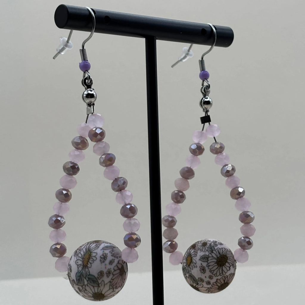 Des boucles d'oreilles pendentif avec des petites perles mauves et une grosse perle fleurie 
