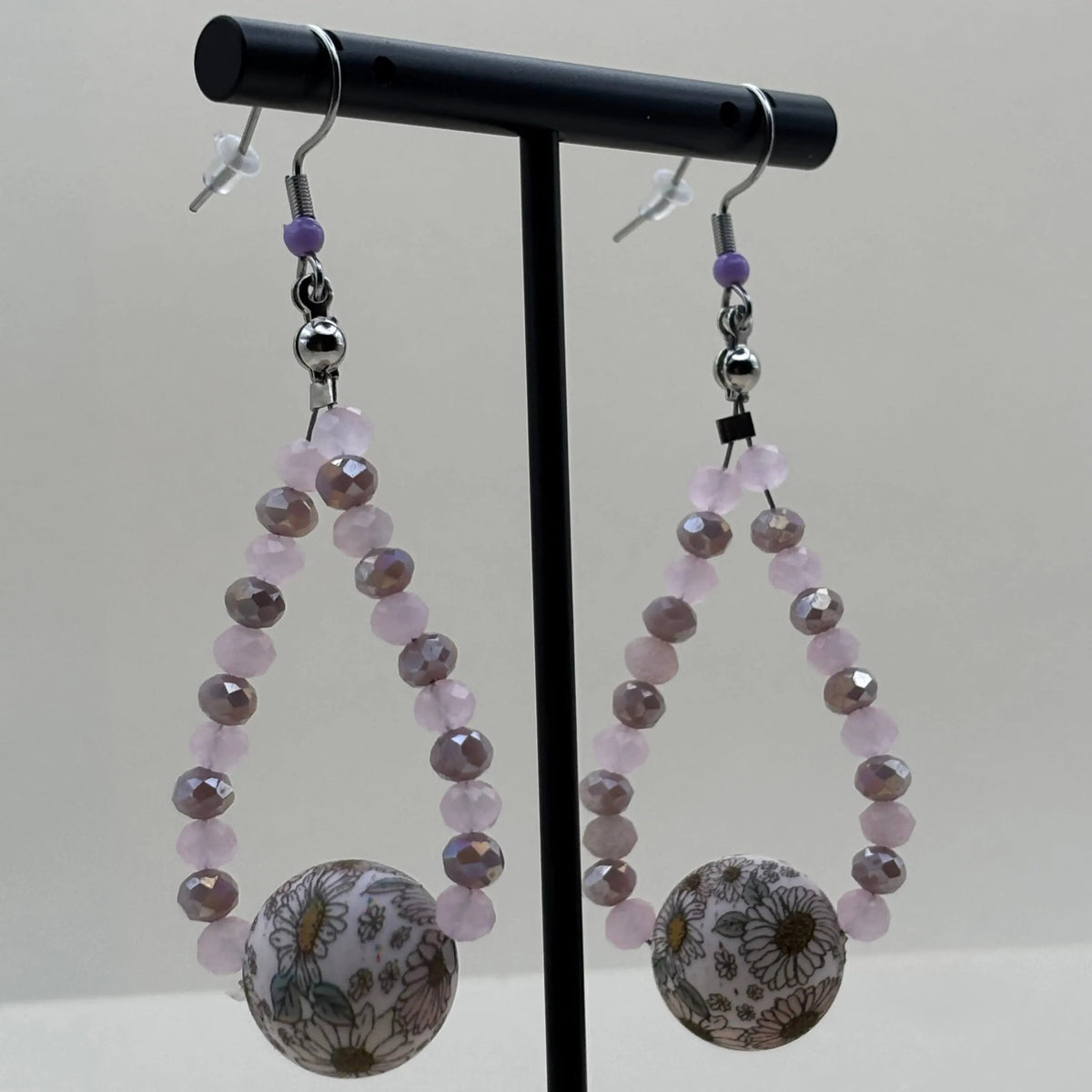 Des boucles d'oreilles pendentif avec des petites perles mauves et une grosse perle fleurie 