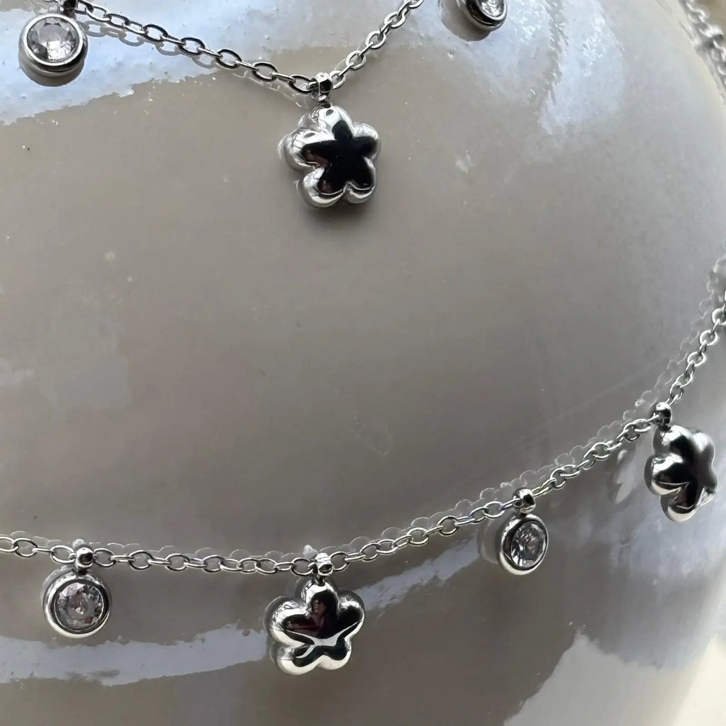 Collier de couleur argentée avec de fins maillons et des breloques en forme d'étoile et de strass