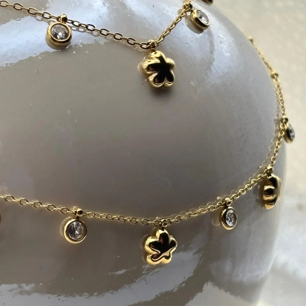 Collier de couleur dorée avec de fins maillons et des breloques en forme d'étoile et de strass