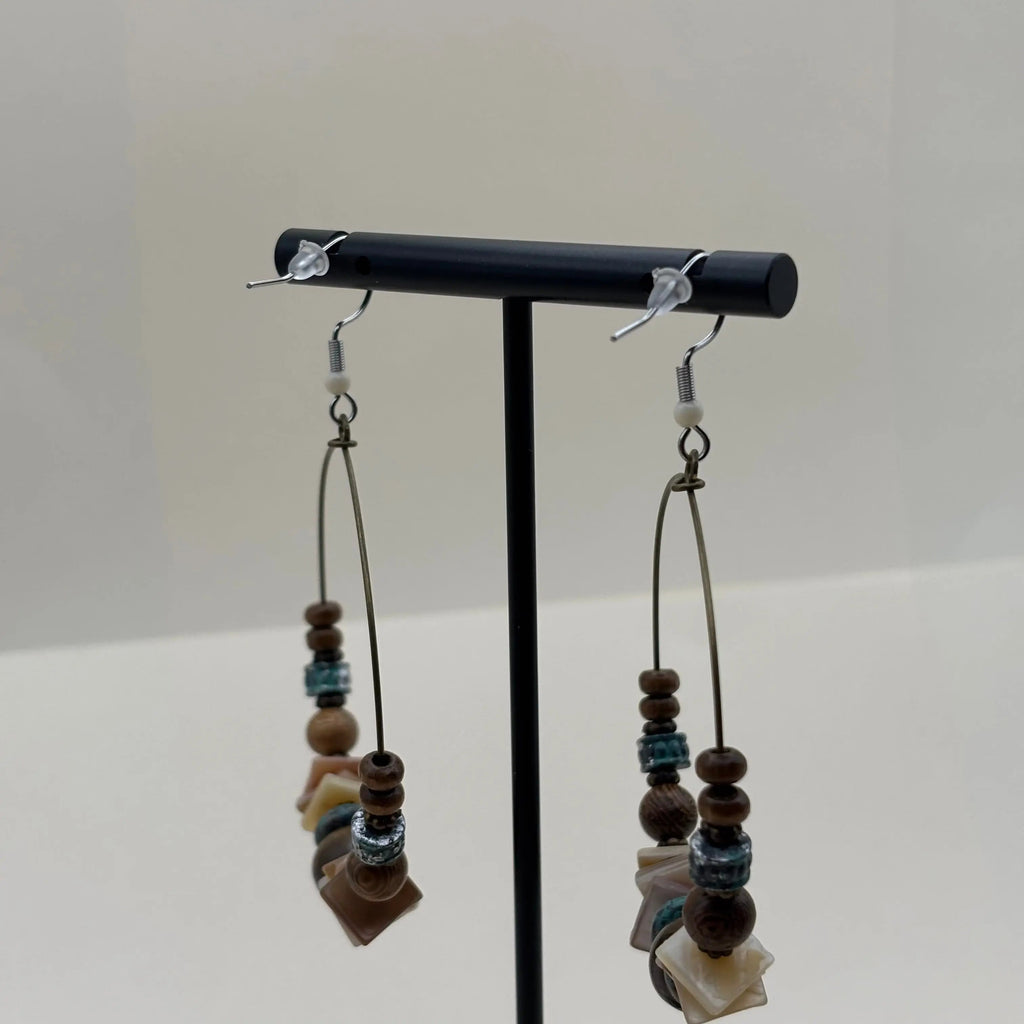 Des boucles d'oreilles créoles avec des perles ronde marron et plates blanches