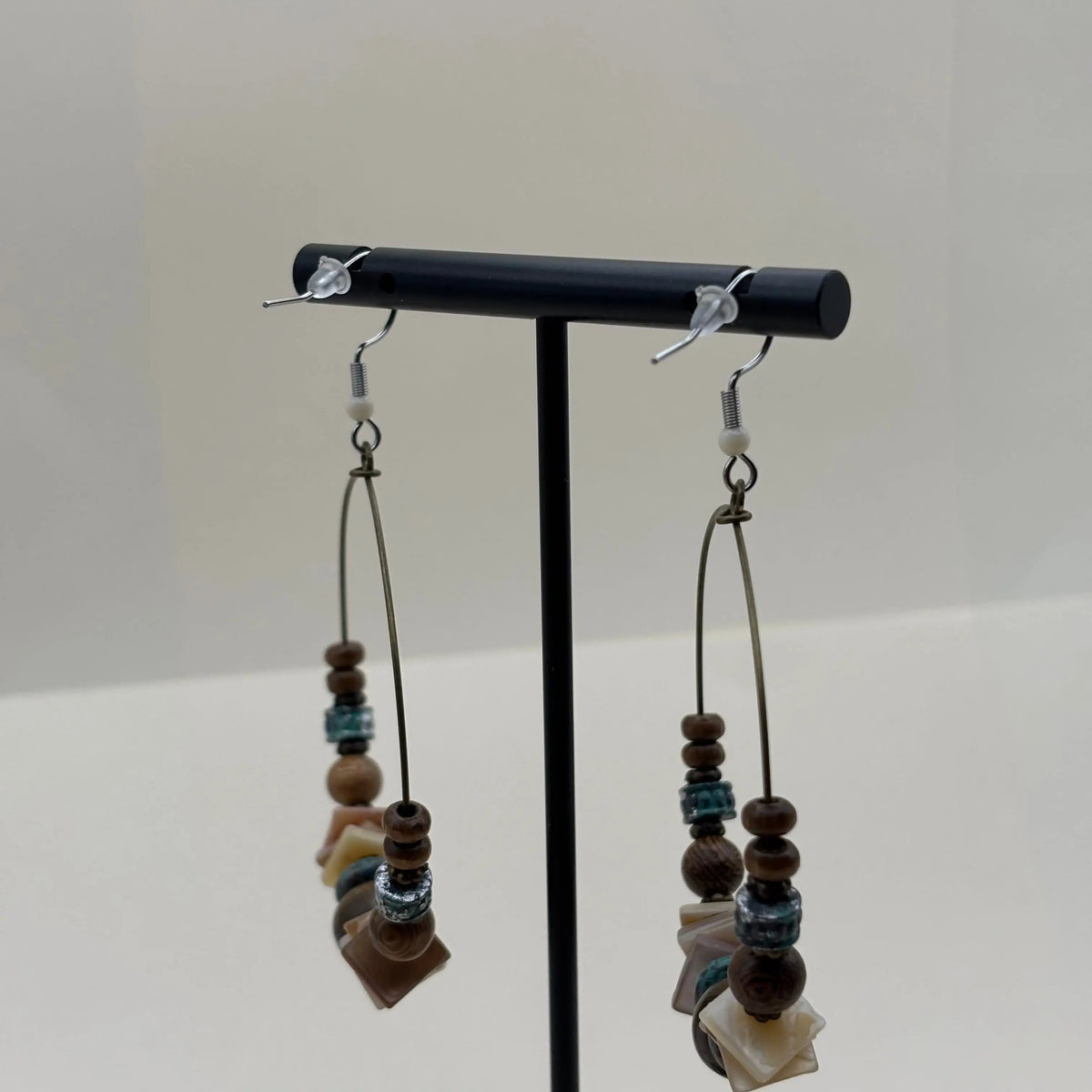 Des boucles d'oreilles créoles avec des perles ronde marron et plates blanches