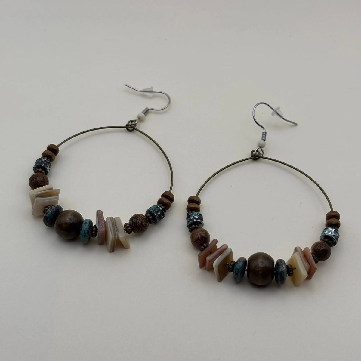Une paire de boucles d'oreilles créoles avec des perles ronde marron et plates blanches