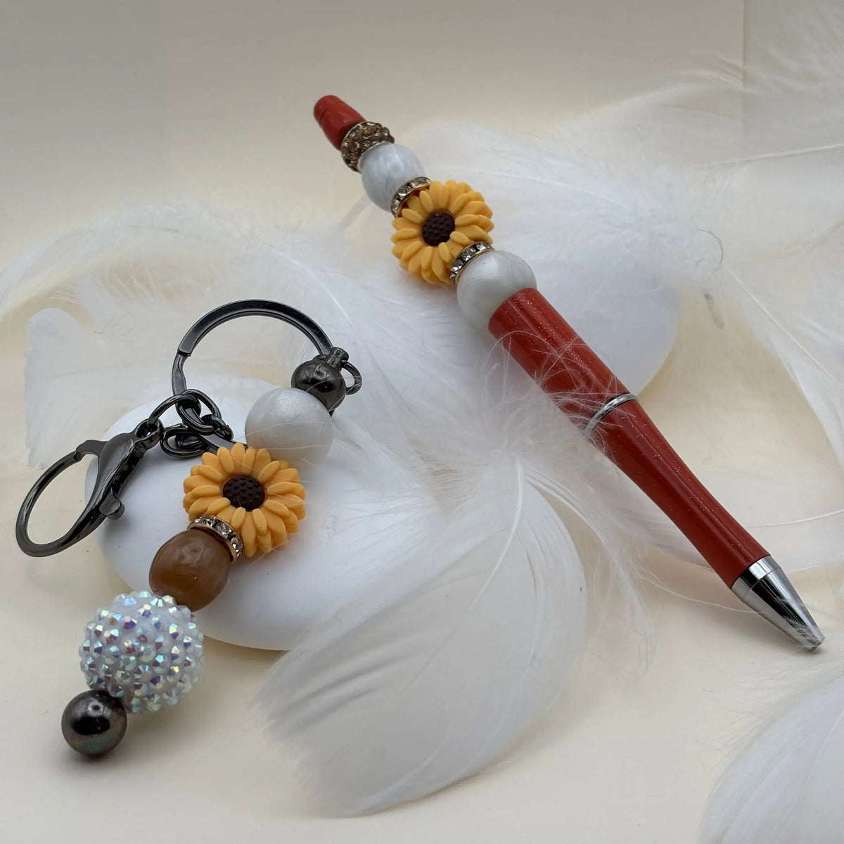 Stylo rouge décoré de fleurs jaunes et perles blanches, présenté avec un porte-clés assorti comprenant une perle irisée