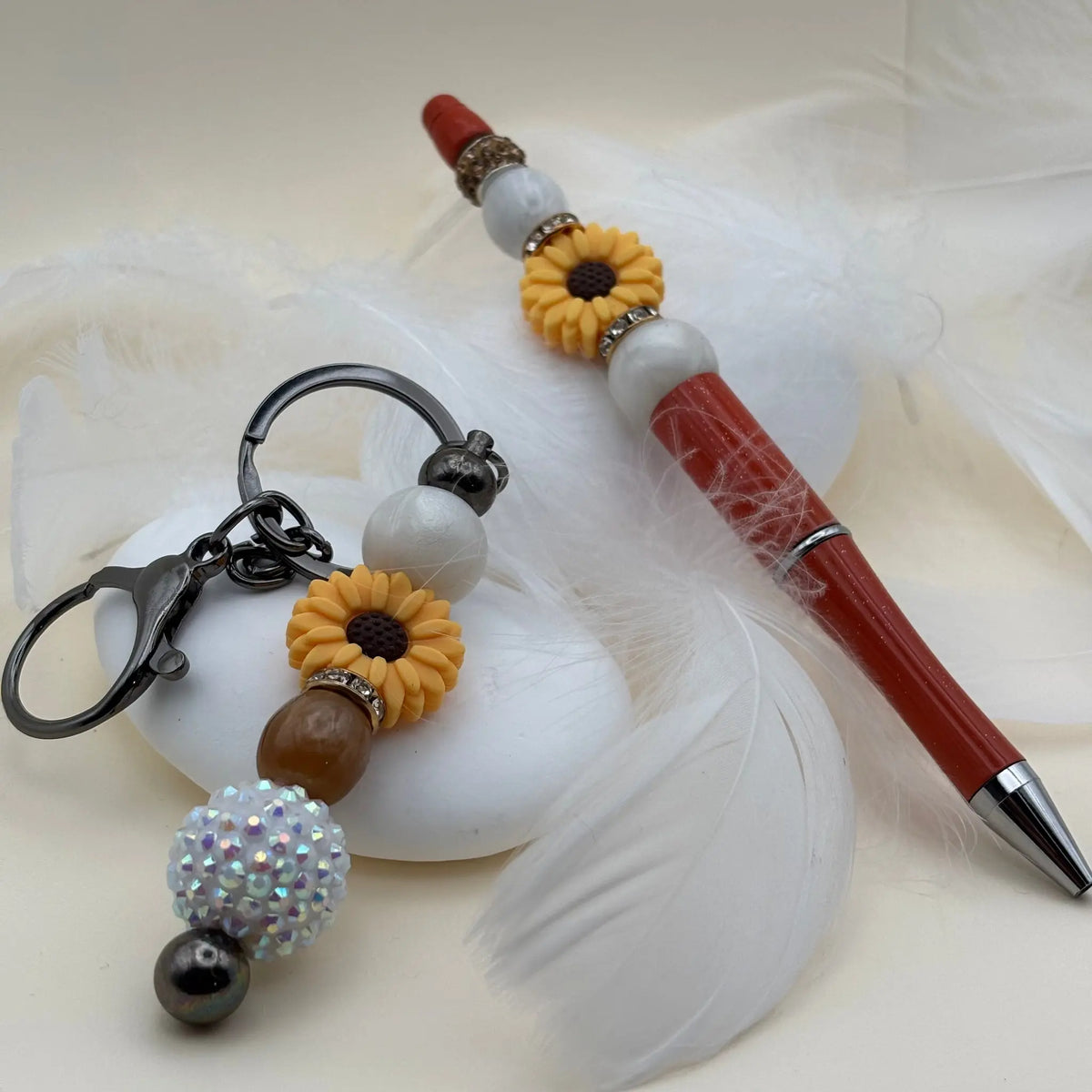Stylo rouge décoré de fleurs jaunes et perles blanches, accompagné d’un porte-clés assorti avec perles iridescentes et marron clair