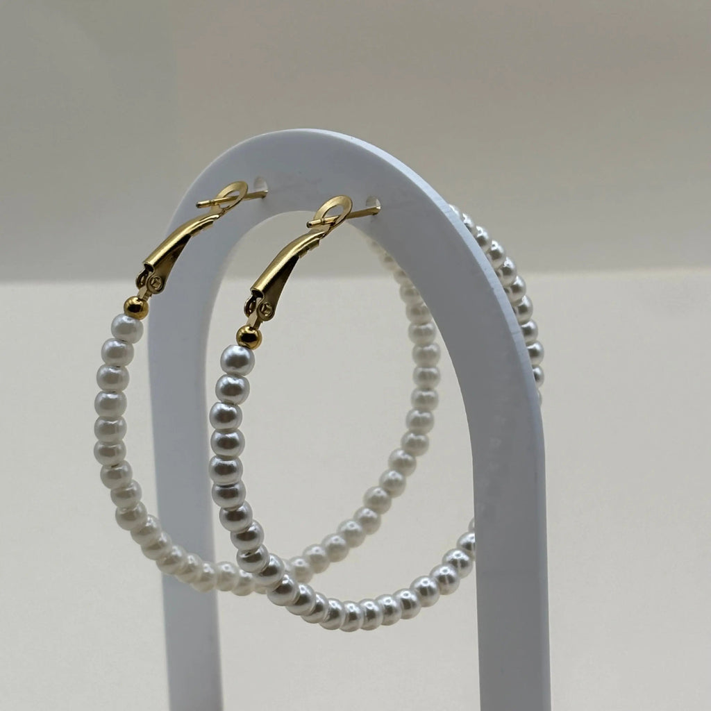 Une paire de boucles d'oreilles créoles en perles acryliques blanches tour en acier inoxydable