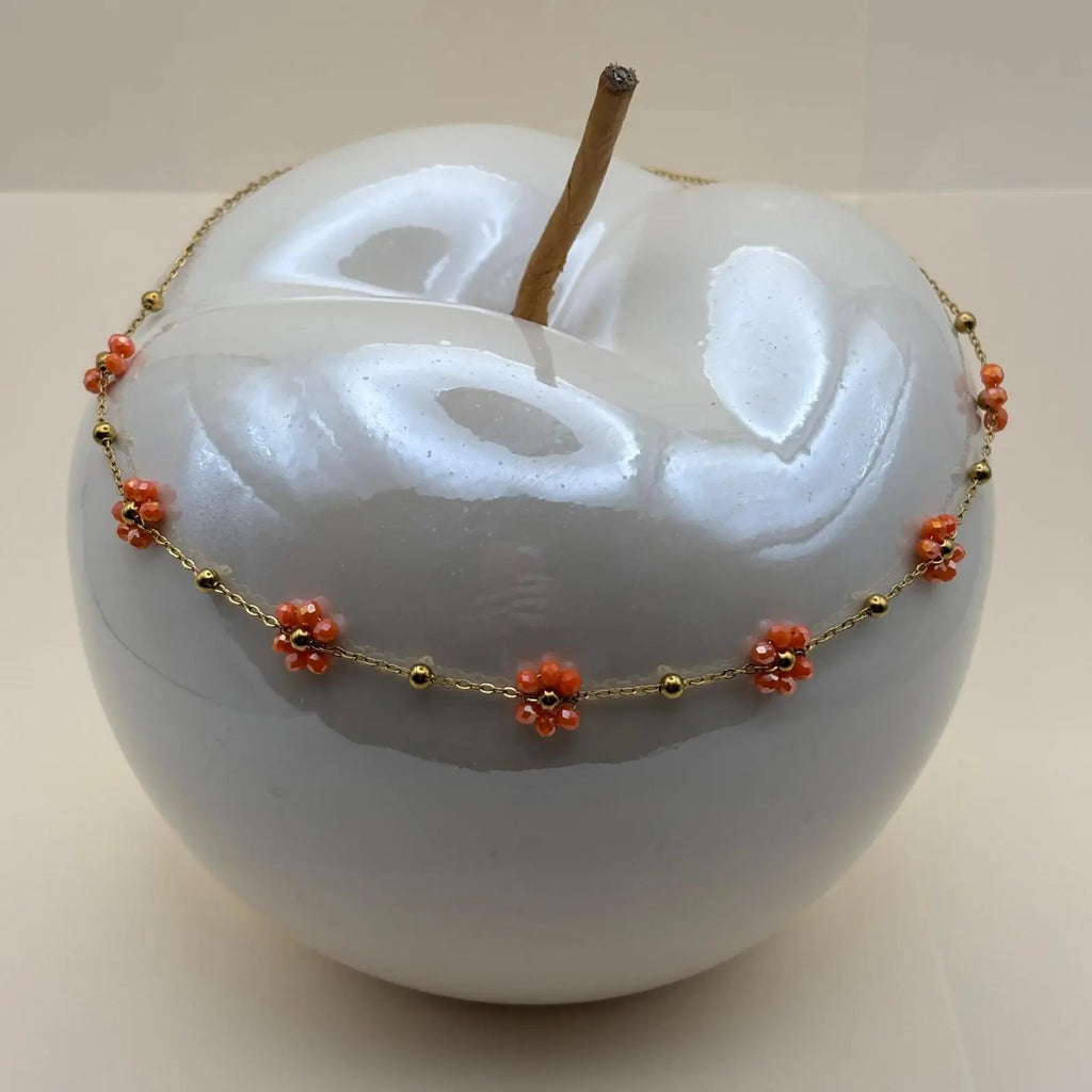 Collier fantaisie avec une chaine dorée à petits maillons et des fleurs colorées orange la chaine est en acier inoxydable 