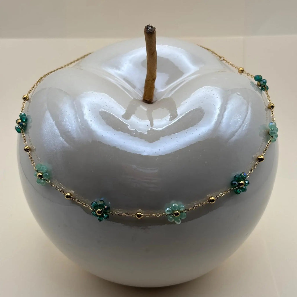 Collier fantaisie avec une chaine dorée à petits maillons et des fleurs colorées vertes la chaine est en acier inoxydable 