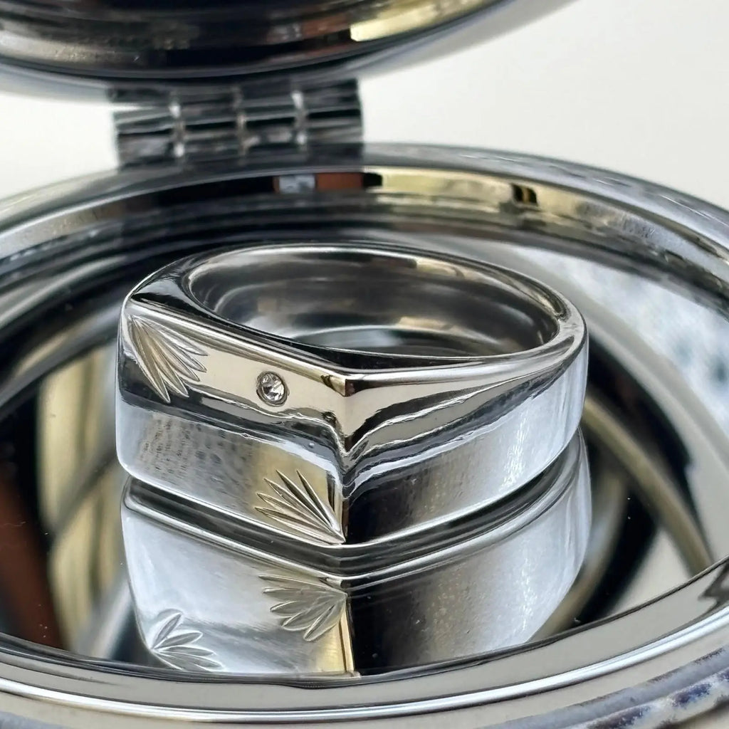 Chevalière argenté de forme rectangulaire avec un strass sur le dessus et des motifs ciselées