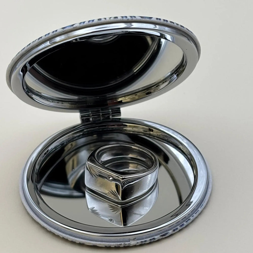 Chevalière argenté de forme rectangulaire avec un strass sur le dessus et des motifs