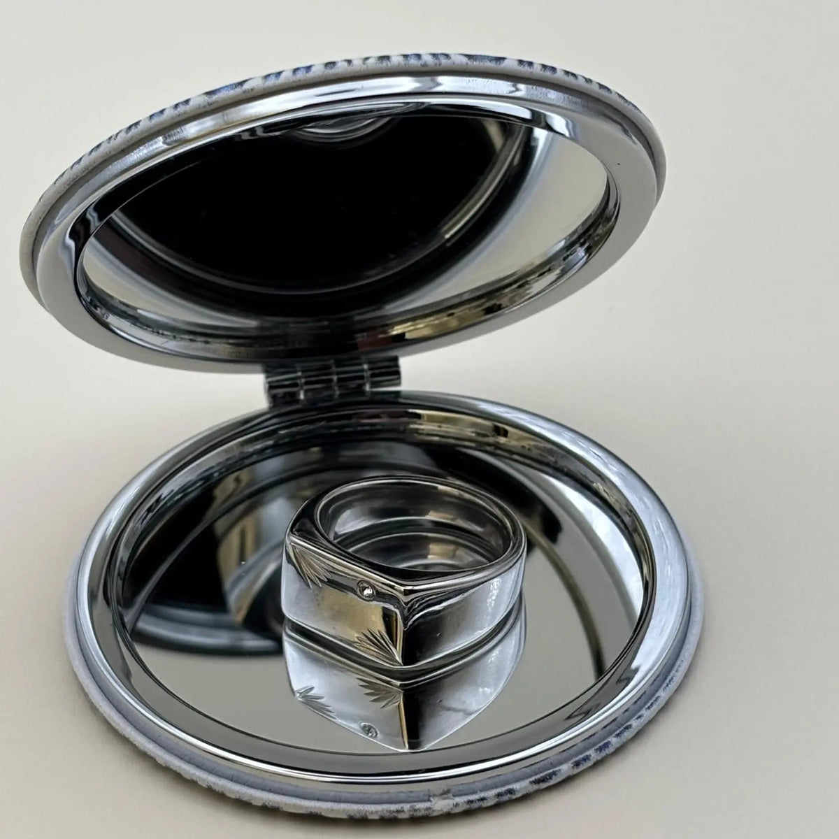 Chevalière argenté de forme rectangulaire avec un strass sur le dessus et des motifs