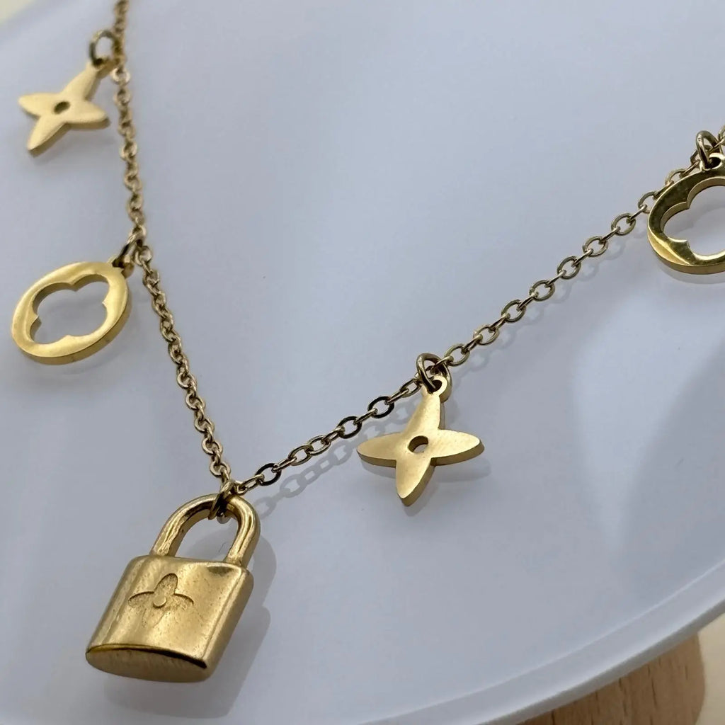 Bracelet de couleur dorée avec des breloques cadenas trèfles et étoiles en acier inoxydable vendu sur le site internet prêtes à briller
