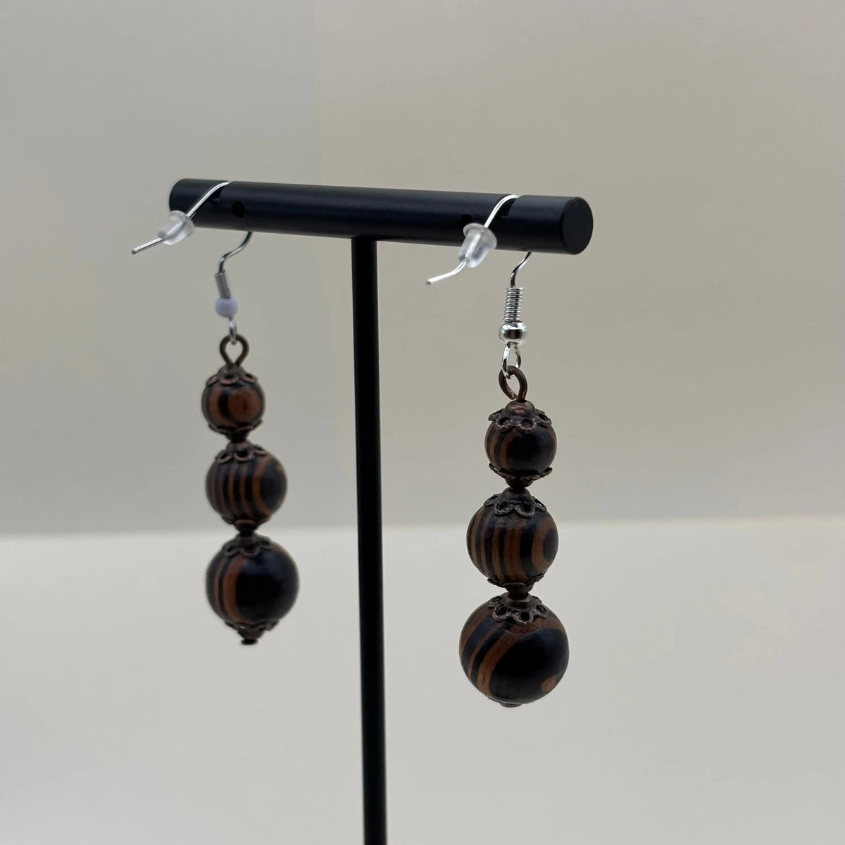 Des boucles d'oreilles artisanales crochet argenté en acier inoxydable et trois perles marbrées marron