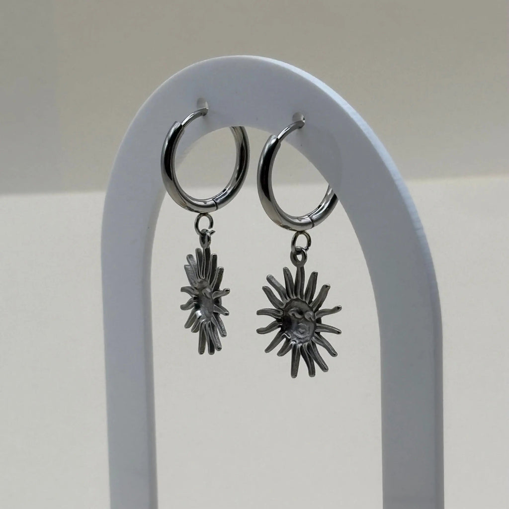 Des boucles d'oreilles argentées petites créoles avec visage dans un soleil  en acier inoxydable