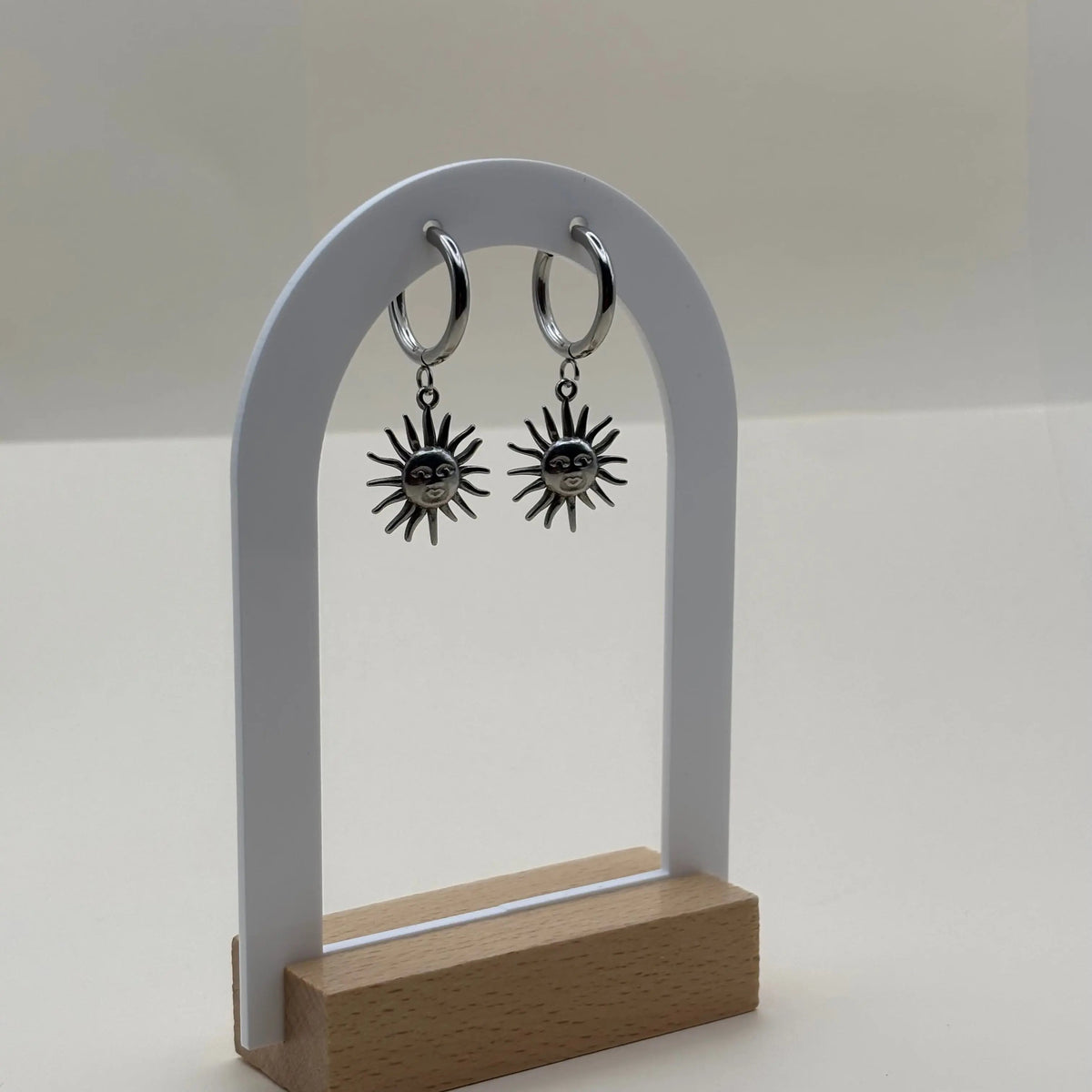 Une paire de boucles d'oreilles argentées petites créoles avec visage dans un soleil  en acier inoxydable