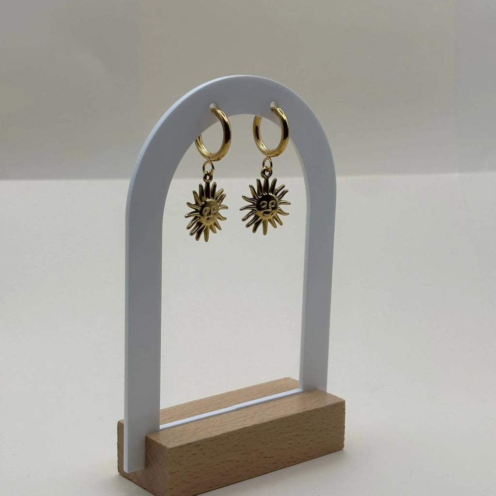 Des boucles d'oreilles dorées petites créoles avec visage dans un soleil  en acier inoxydable