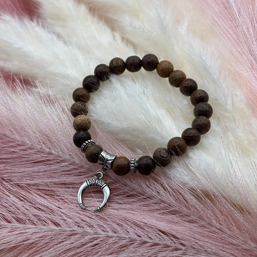 Vue de près d'un bracelet en perles artisanal avec une breloque lune argentée et des perles en bois sur élastique