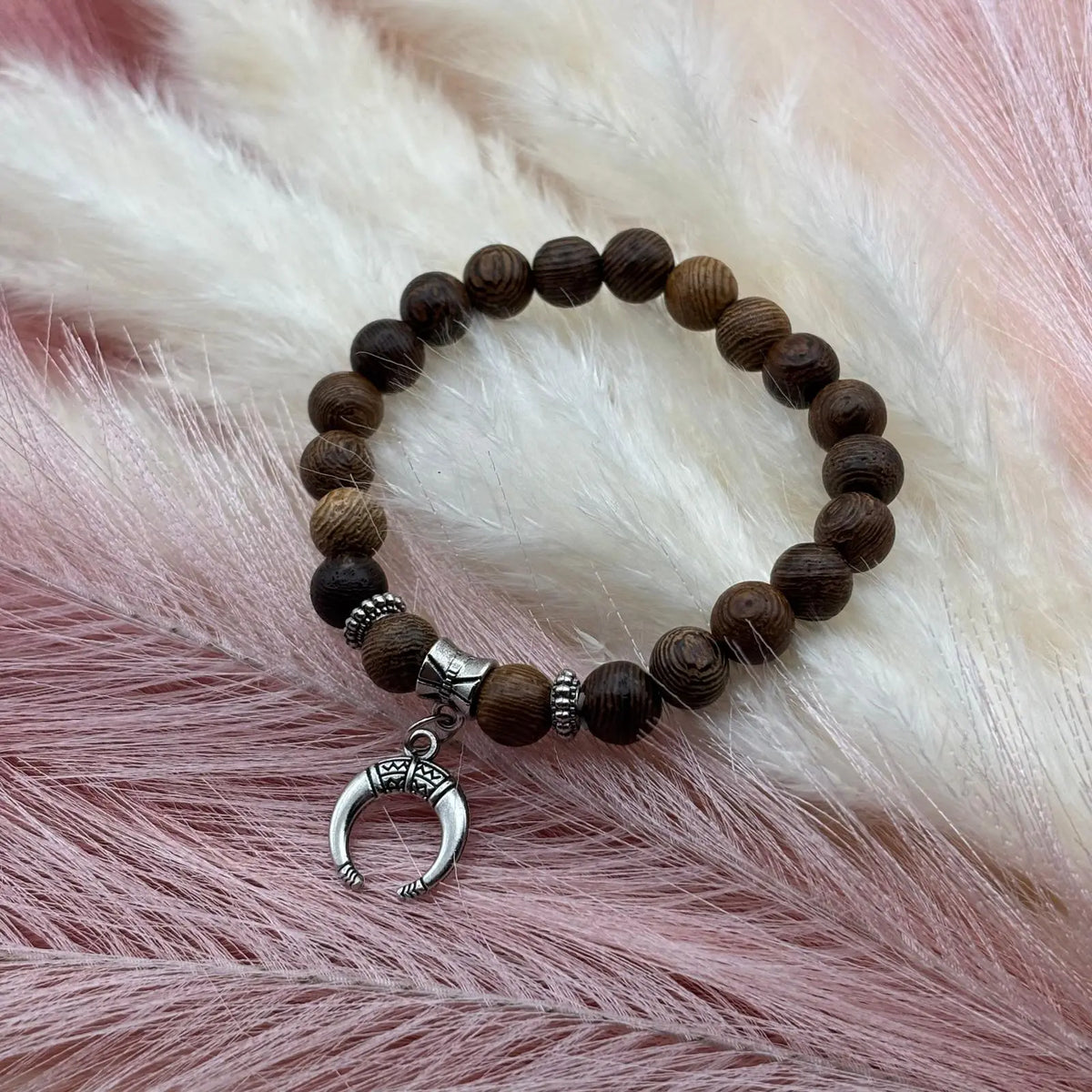 Vue de près d'un bracelet en perles artisanal avec une breloque lune argentée et des perles en bois sur élastique